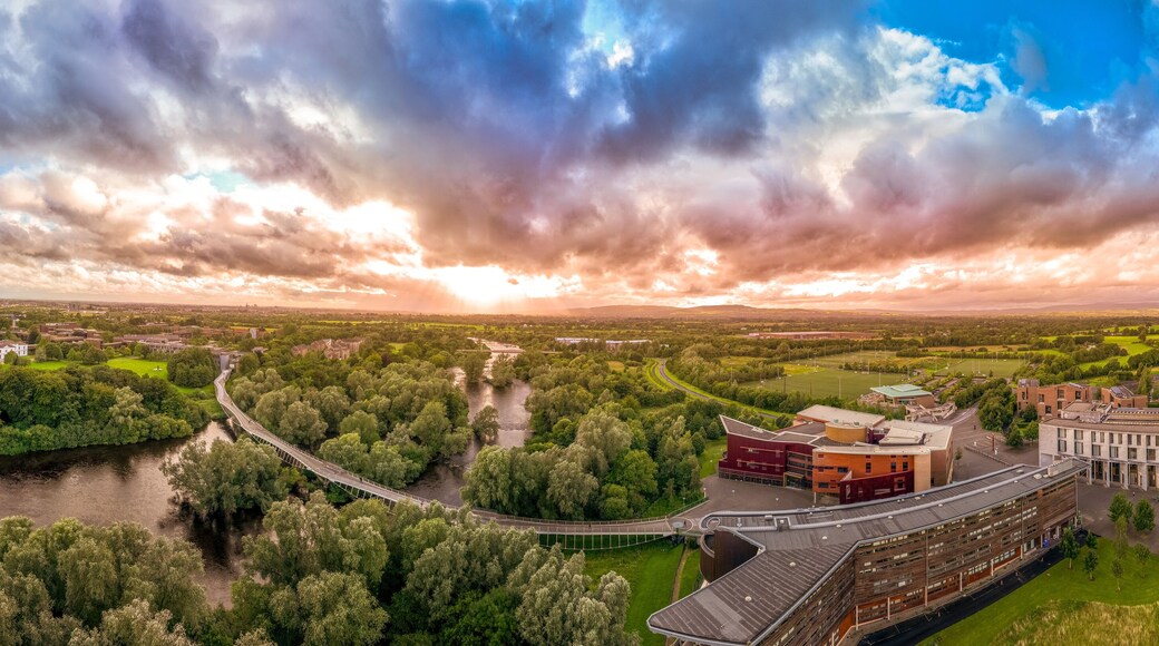 Aerial panoramic view of Living Bridge, curving modern pedestrian crossing over the Shannon river at the University of Limerick with stunning sunset