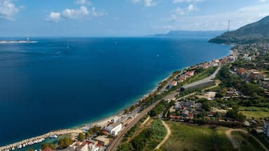 A coastal town with a beach, a lighthouse, and a mountainous backdrop.