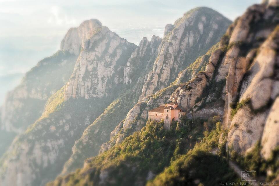 A mountain landscape with a small building nestled among rocky cliffs.