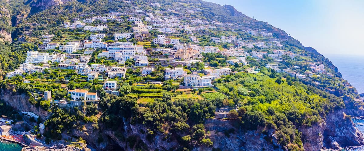 A coastal town with buildings nestled on a hillside, overlooking the sea.