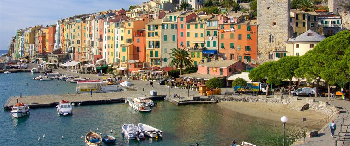 A coastal town with colorful buildings, a marina with boats, and a historic castle on a hill.