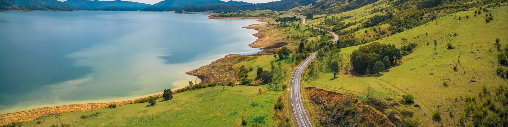 Road winding through lake shore and mountains. Scenic aerial panorama of Australia
