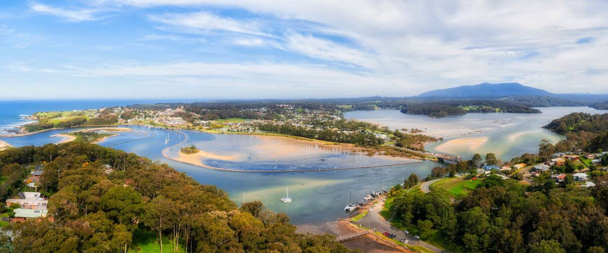 A coastal landscape with a bay, a bridge, and a mountain in the distance.