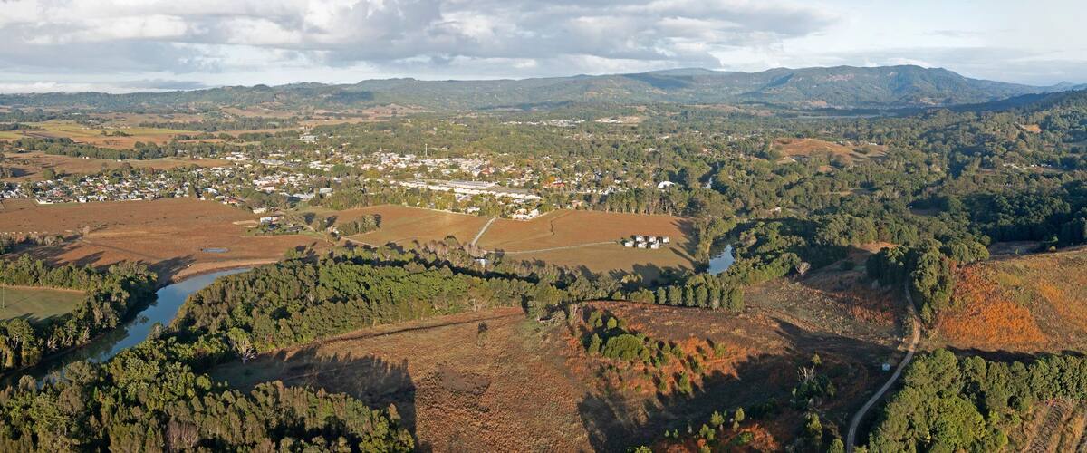A rural landscape with a small town nestled among rolling hills and dense forests.