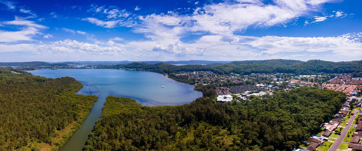 A lake surrounded by forest, a river, and a town with houses.