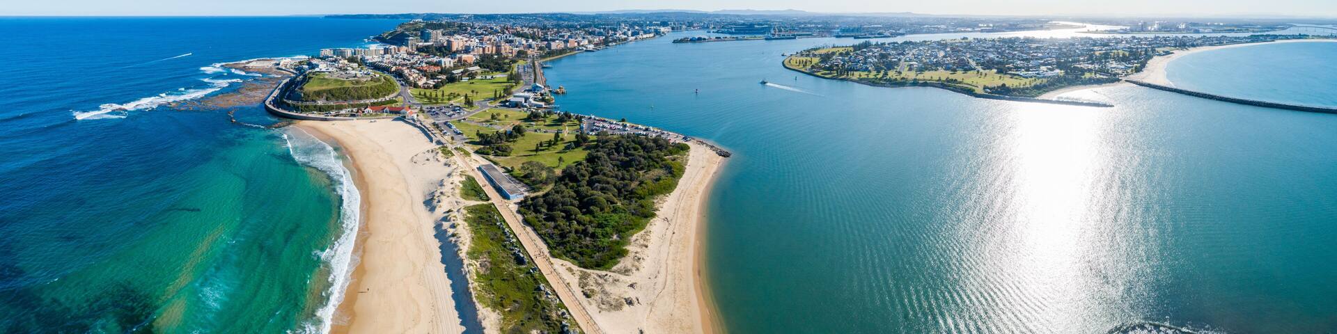 A coastal city with a long sandy beach, a large body of water, and a dense urban area with buildings.