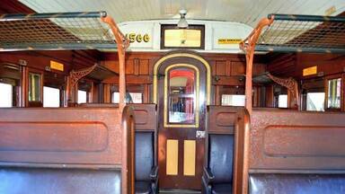The interior of a vintage train with wooden panels and a vintage clock.