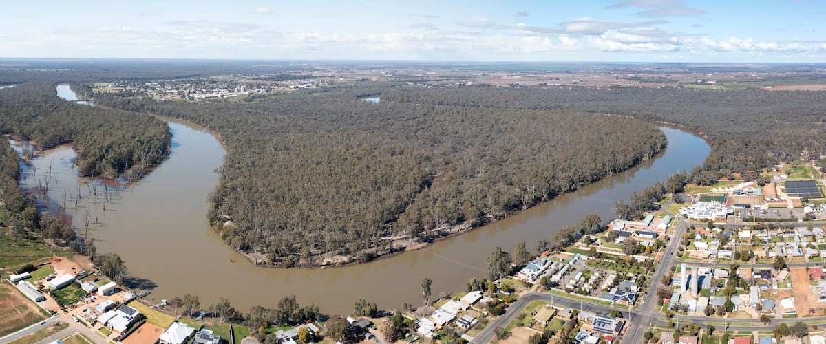A river winding through a forested area with a town on the right.