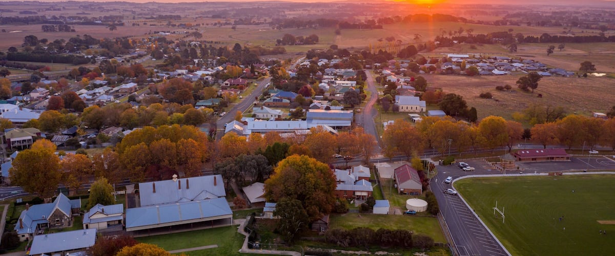A rural town at sunset with houses, roads, and fields.