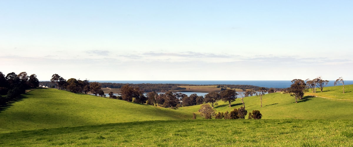 Central Tilba in its idyllic setting near Narooma. Autumn scene in rural New South Wales Australia. Farmland fields, trees, ponds and hills.