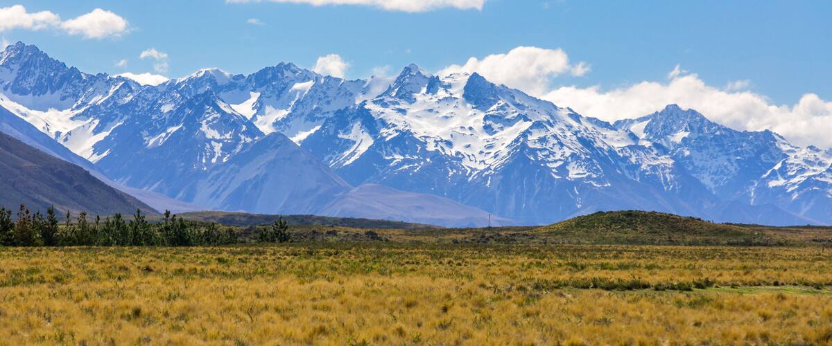 A mountain range with snow-capped peaks under a clear blue sky.