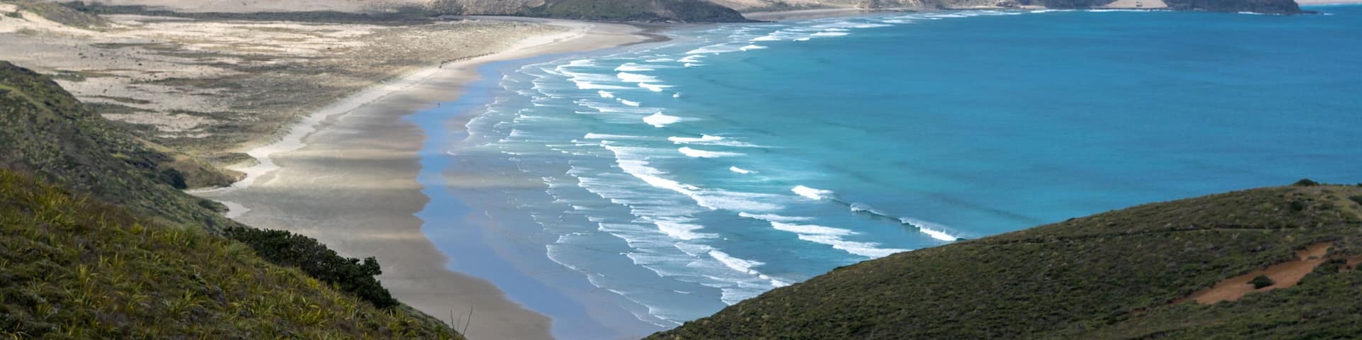 Ninety Mile Beach on the Pacific Ocean shore with a blue sky in the background, New Zealand