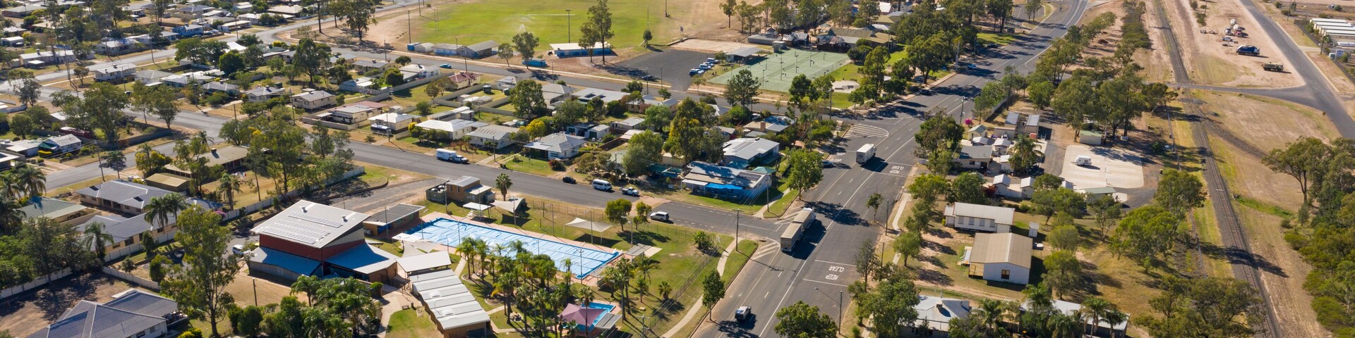 An aerial view of a residential area with houses, roads, and a railway track.
