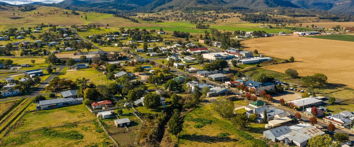 A rural town with houses, fields, and mountains in the background.