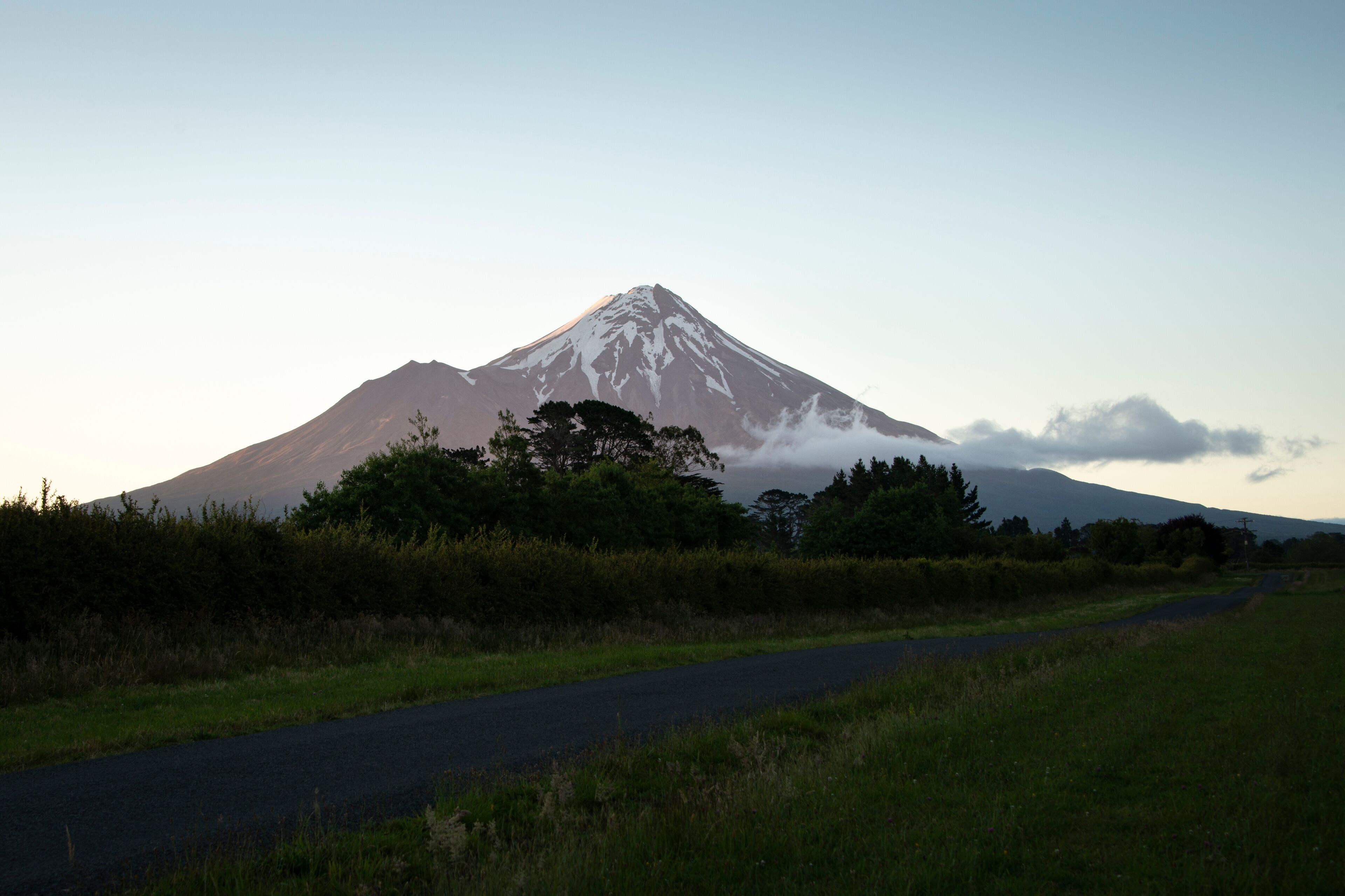 A snow-capped mountain with a road in the foreground.
