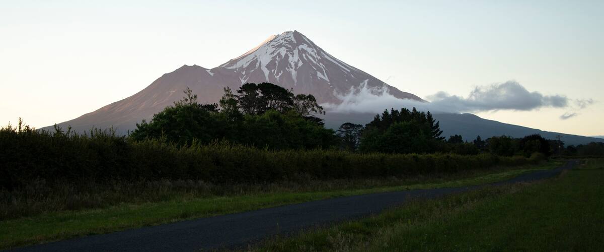 A snow-capped mountain with a road in the foreground.
