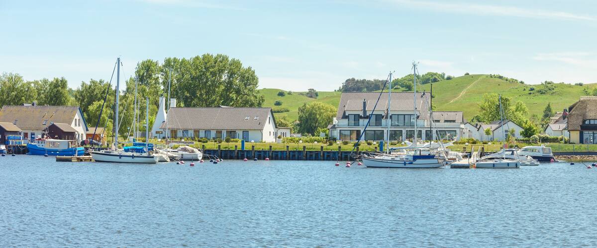 A harbor with boats, a large building, and a green hill in the background.
