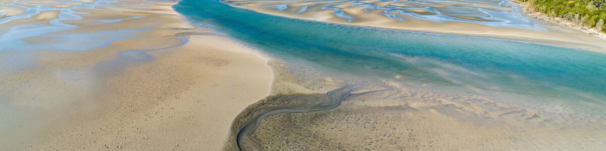 Panorama of coastline with ripples and patterns in the sand.