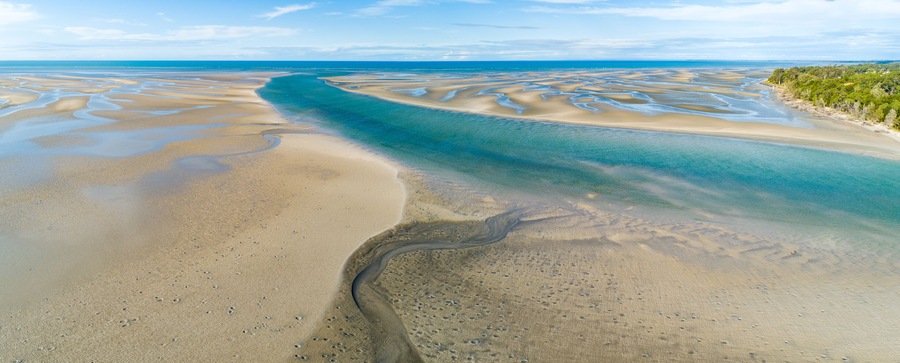 Panorama of coastline with ripples and patterns in the sand.