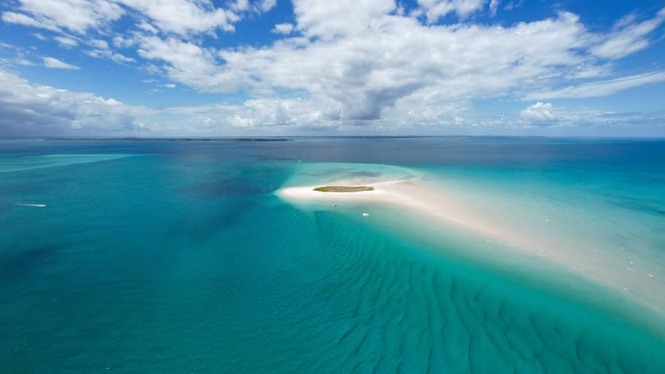 A turquoise sea with a small island and a clear sky.
