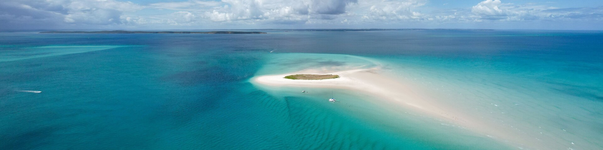 Un mar turquesa con una pequeña isla y un cielo despejado.