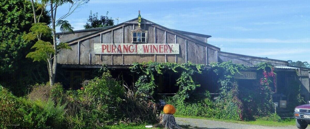 A rustic building labeled "Puranji Winery" with a wooden structure and vines growing on it.