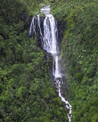 A multi-tiered waterfall cascading through a dense, green forest.