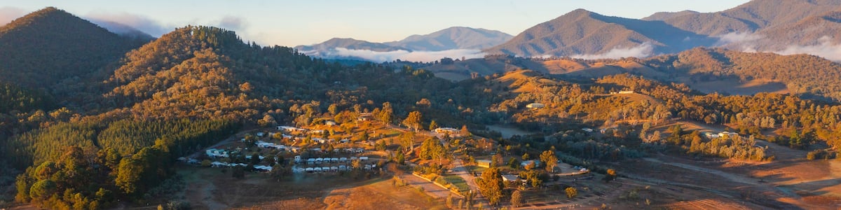 A valley with a small settlement surrounded by mountains and a blanket of clouds.