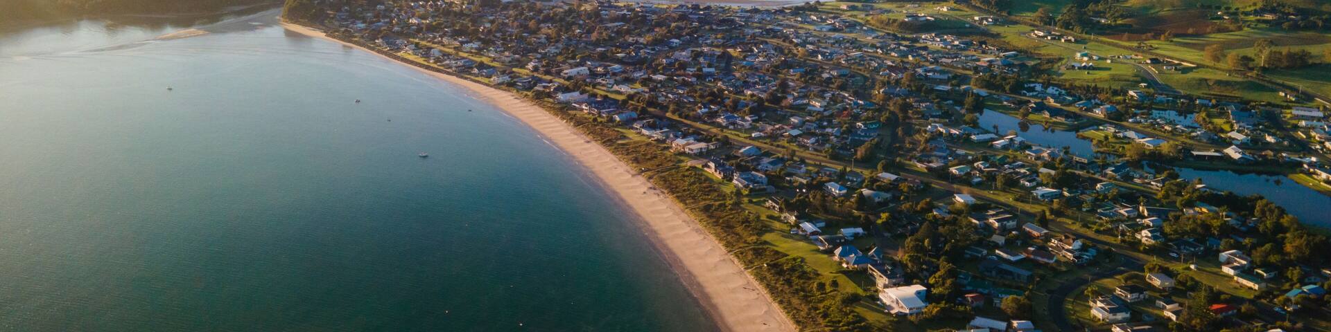 A coastal town with a beach, a river, and rolling hills in the background.