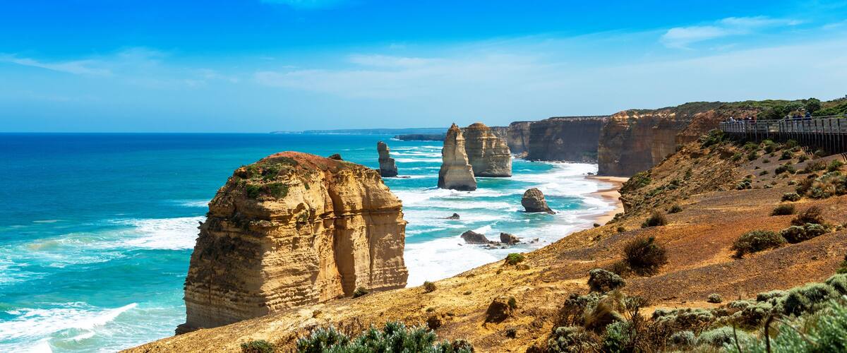 A coastal landscape with prominent rock formations and a clear blue sea.