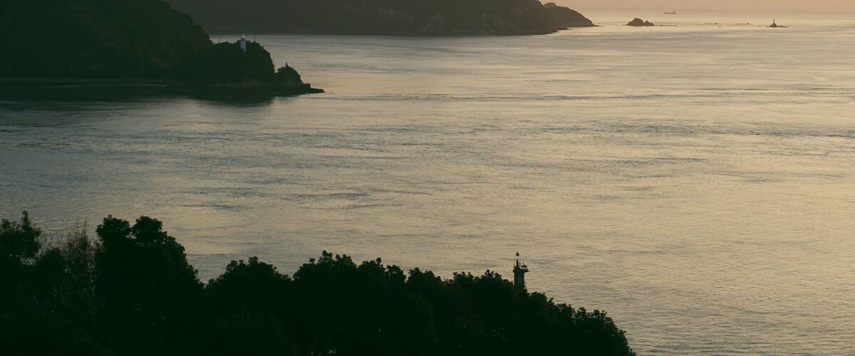 A coastal landscape with mountains and calm sea.