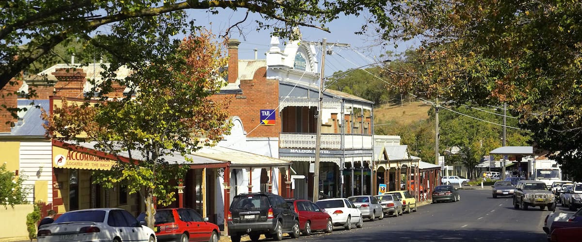 A street lined with vintage buildings, parked cars, and trees.