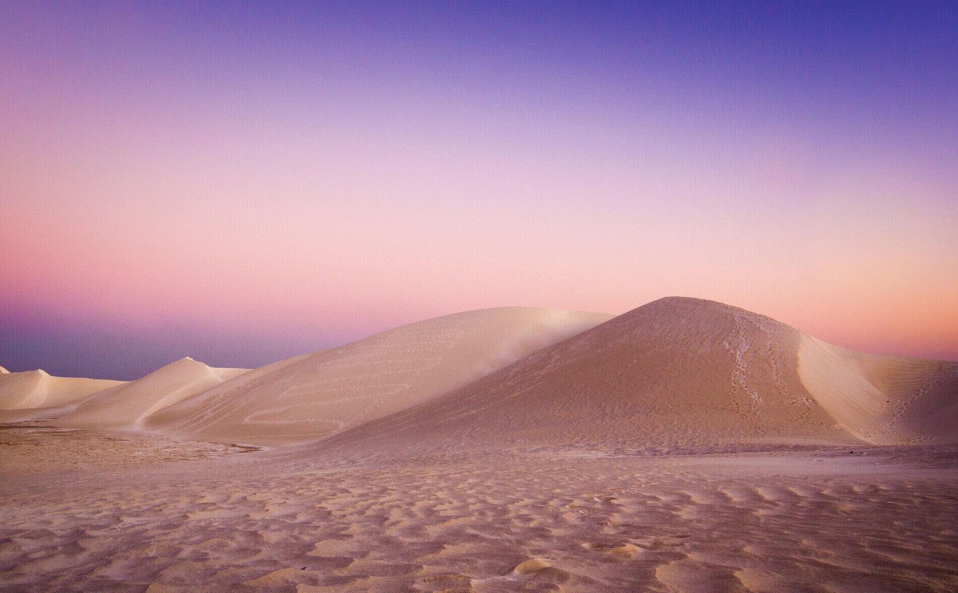 A desert landscape with sand dunes under a twilight sky.