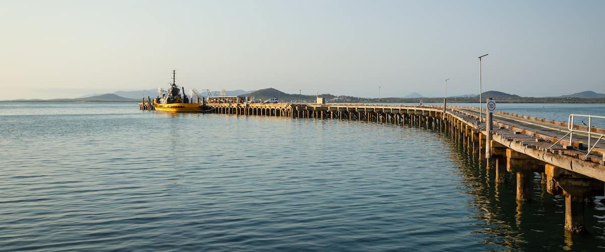 A pier extending into calm waters with a yellow boat docked at the end.