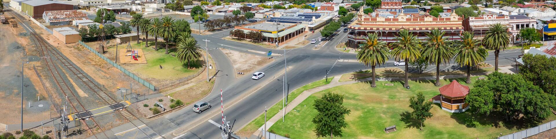 Aerial panorama view of parkland and shops around a large intersection on a regional town