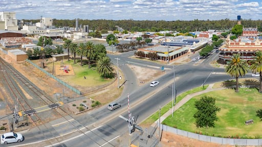 Aerial panorama view of parkland and shops around a large intersection on a regional town
