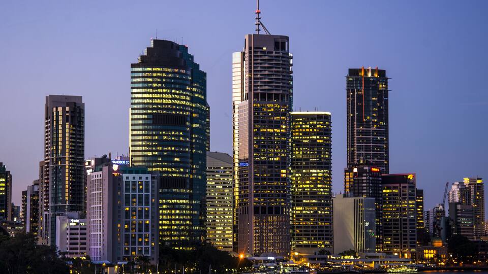 A city skyline with illuminated high-rise buildings and a marina with boats.