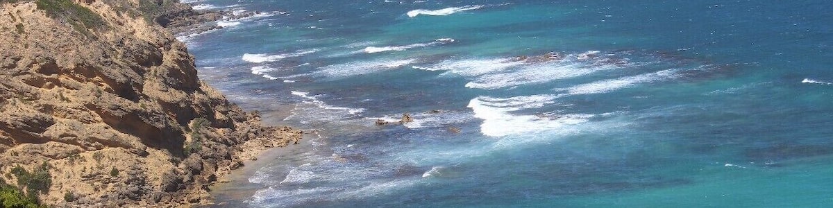 A coastal landscape with rocky cliffs and turquoise waters.