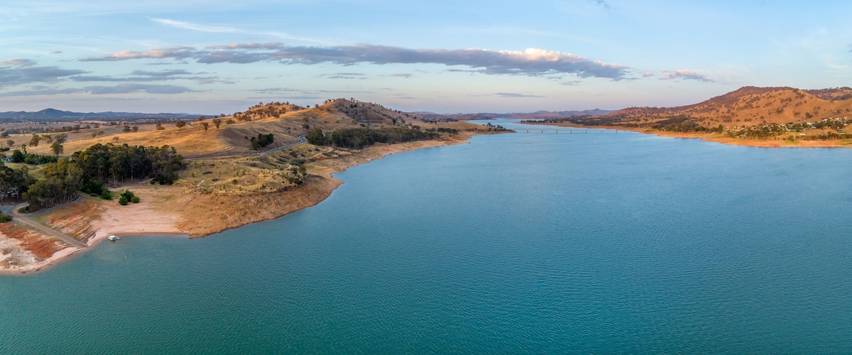 A river winding through a hilly landscape with sparse vegetation and a few scattered houses.