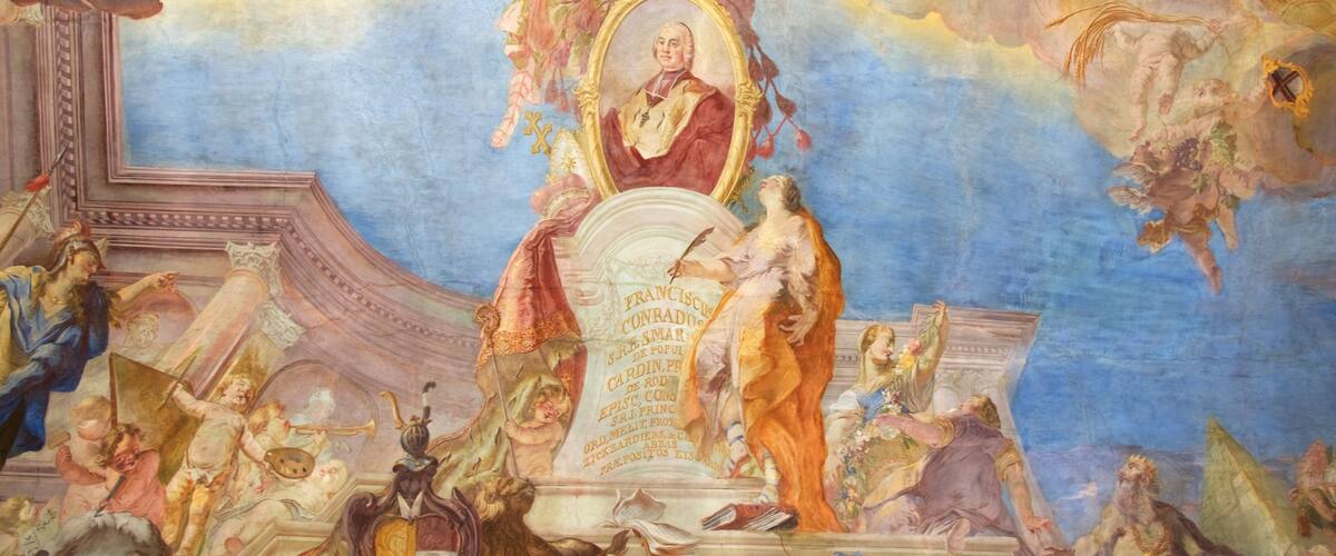 A fresco mural with a central figure on a pedestal, surrounded by cherubs and classical architectural elements.