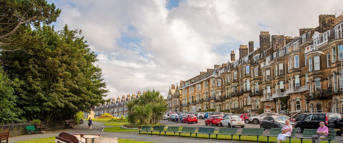 A row of terraced houses with a park and a statue in the foreground.