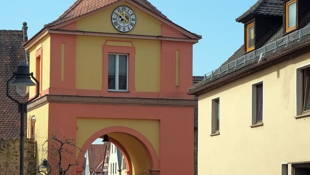 A yellow building with a clock tower and an archway.