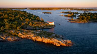 Aerial view of Pointe au Baril Lighthouse, islands, and forest with rocky shoreline at sunset, Georgian Bay, Canada.