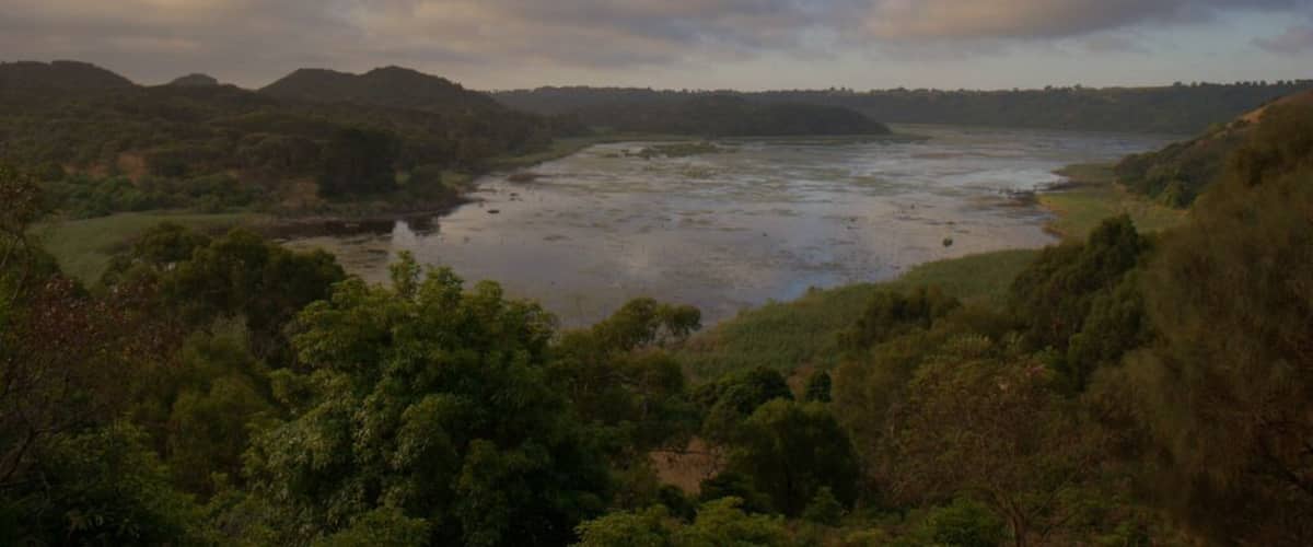 A river meandering through a lush valley with hills in the background.