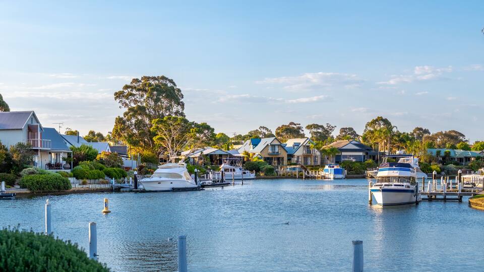 A marina with boats docked, surrounded by houses and trees.