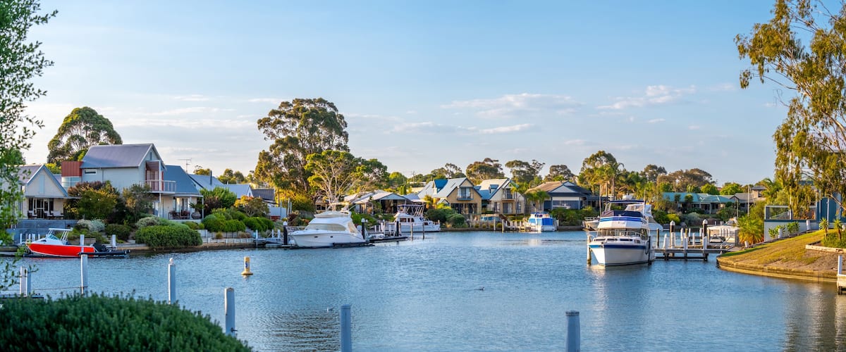 A marina with boats docked, surrounded by houses and trees.