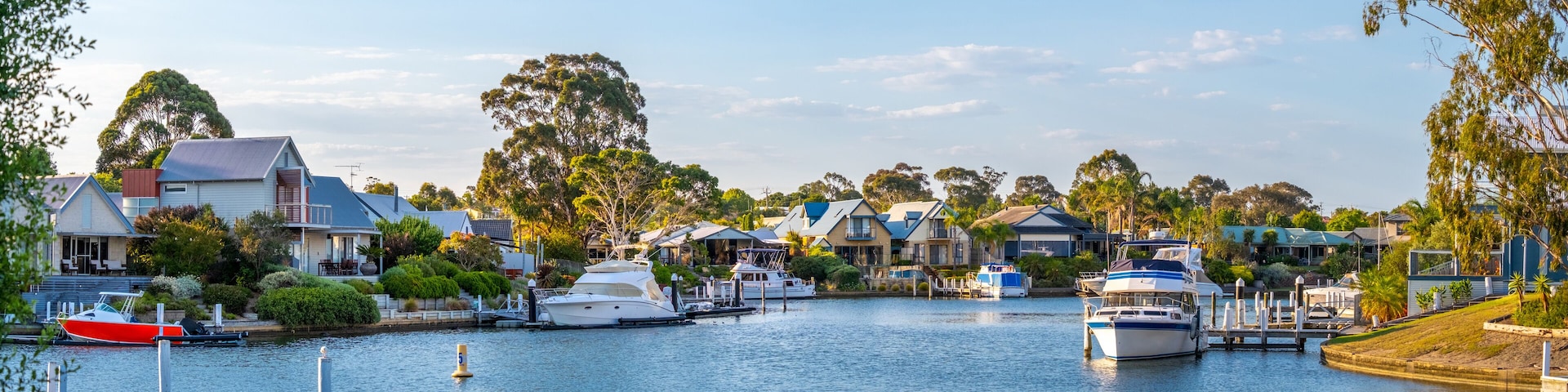 A marina with boats docked, surrounded by houses and trees.