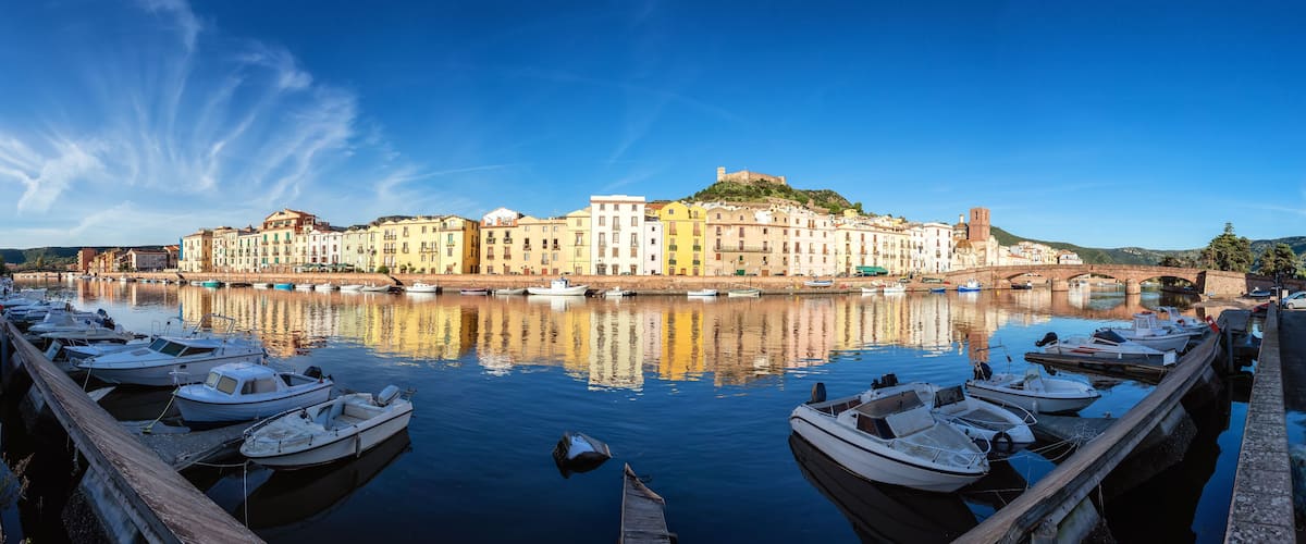 A harbor with boats docked, a bridge, and colorful buildings along the waterfront.