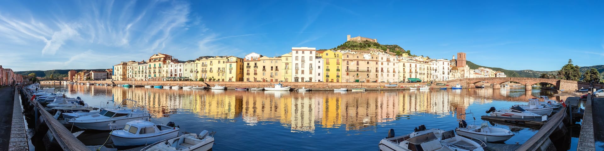 A harbor with boats docked, a bridge, and colorful buildings along the waterfront.