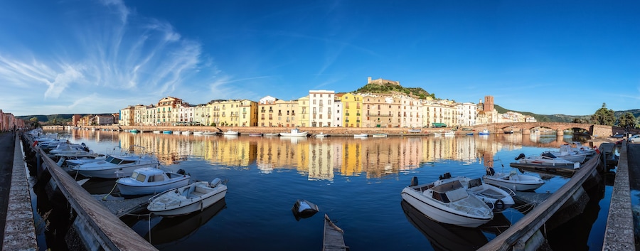 Un port où sont amarrés des bateaux, un pont et des bâtiments aux couleurs vives qui bordent le quai.